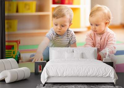 Preschool boy and girl playing on floor with educational toys. Children toddlers at home or daycare. Wall mural