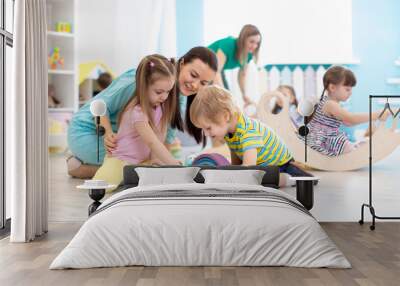 Preschool children play with teacher in kindergarten Wall mural