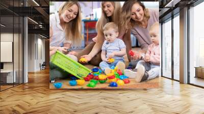 Three woman friends with babies toddlers playing on the floor in sitting room Wall mural