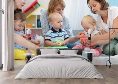 Toddler babies with moms in playroom in nursery Wall mural