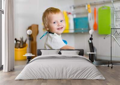 Toddler child washing dishes in kitchen. Little boy having fun with helping to his mother with housework Wall mural