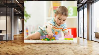 Toddler playing with toys on a white carpet at home Wall mural