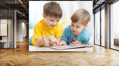 two children looking at book Wall mural