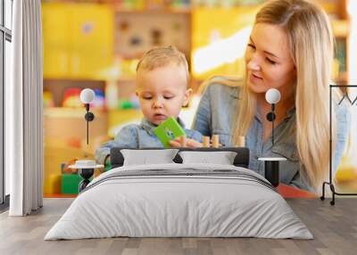 young teacher studying with baby toddler in kindergarten Wall mural