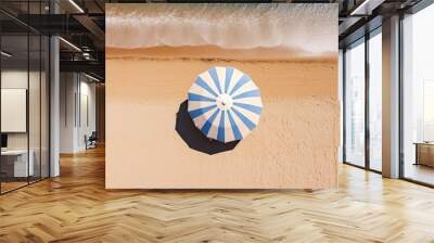 Striped beach umbrella on sandy coast, top view Wall mural