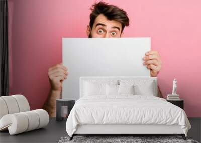 Surprised man peeking over a blank white sign, potential for advertisement or message display. Man Holding Blank White Sign Wall mural