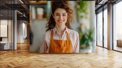 A smiling woman hostess in an orange apron with in apartments. Wall mural