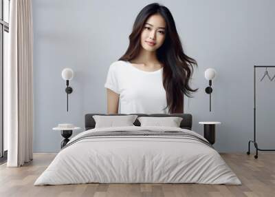 Young beautiful asian woman model with long hair in white t-shirt posing on light grey background. Wall mural