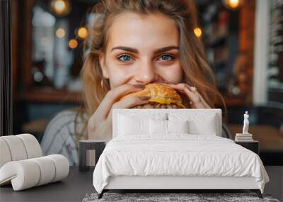 Young woman eating hamburger and looking at camera Wall mural