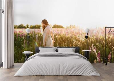 young woman dancing on a wildflower field with sunrise on the background. freedom concept. Wall mural