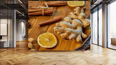 A big piece of ginger on wooden brown background. Ingredients for mulled wine: dried fruits, orange, ginger, cinnamon, anise stars and nuts. Close up view Wall mural