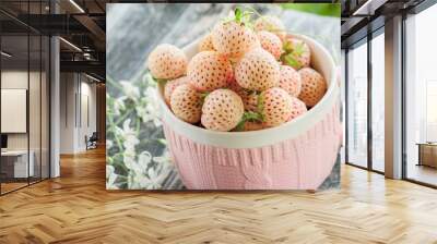 Ripe fresh pineberries in a pink Cup in a rustic style with small white flowers close-up Wall mural