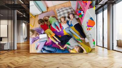 Active kids laying on soft pillows and mats at the kindergarten Wall mural