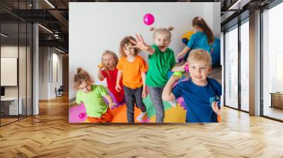 Energetic youngsters throwing away many colorful balls Wall mural