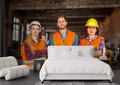 Factory workers in orange protective vests during work Wall mural