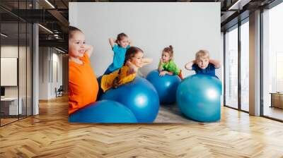 Kids doing physical exercises on large fitballs Wall mural