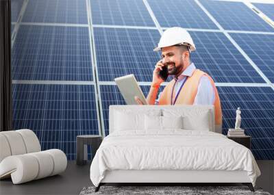 The young electrician works at a solar station using gadgets Wall mural