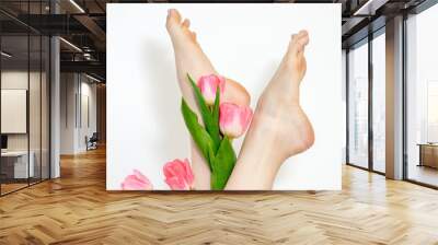 Beautiful slim smooth woman's legs with tulips flowers on white background Wall mural