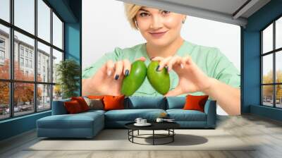 Female nutritionist doctor wearing green workwear holding green organic avocado fruit. Healthy lifestyle concept Wall mural