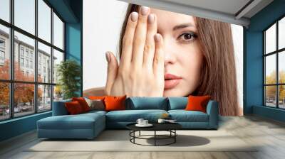 Portrait of young woman is covering face with her hand on white background. Wall mural