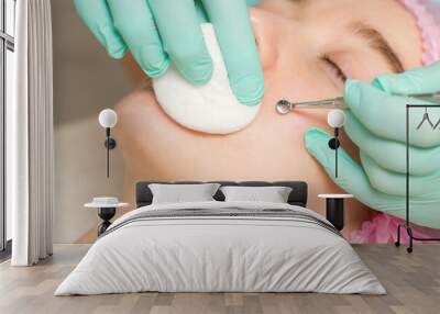 The beautician removes blackhead and acne on the female face in a beauty salon, blackhead removal tool Wall mural