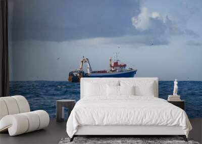 Fishing vessel during the industrial harvesting of wild marine products by deep-sea trawl. Wall mural