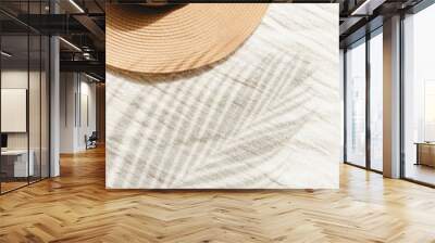  Straw hat and palm leaf shadow on beige linen cloth material background Wall mural