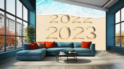 New Year concept photo of coming 2023 and leaving 2022. Blue sea wave washing away the handwritten in sand numbers. Sandy beach background. Wall mural