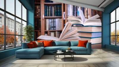 Books lie on the table against the background of bookcases. Wall mural