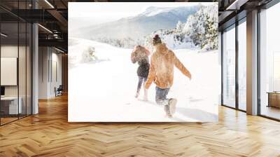 Man and woman running after each other in snow glittering in the sun Wall mural