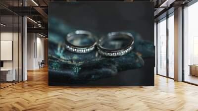 Two white golden wedding rings with diamonds on metal Buddha hand on dark background. Spiritual love concept. Wall mural