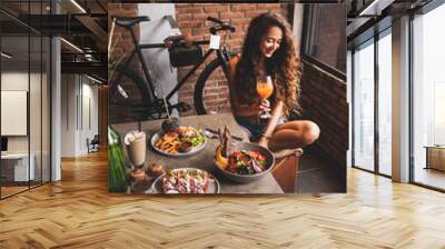 Woman enjoying fresh organic vegetarian food and glass of kombucha in hipster style cafe with bicycle design Wall mural