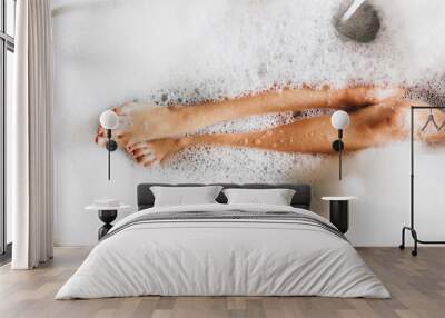 Woman legs in bath foam. Top view. Enjoying and relaxation in spa hotel Wall mural