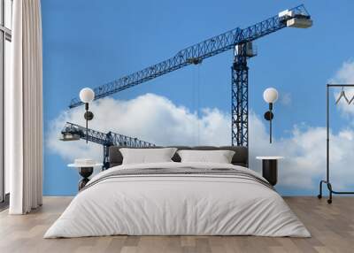 Construction cranes on background of blue sky and white clouds Wall mural