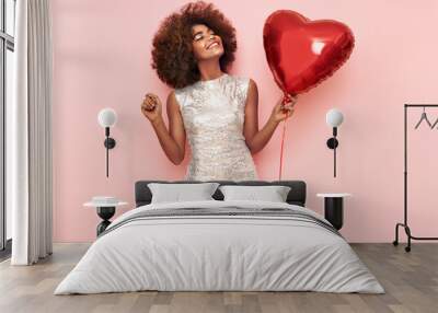 a beautiful young african-american woman with heart shape air balloon on a pink background. woman on Wall mural