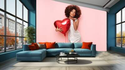 a beautiful young african-american woman with heart shape air balloon on a pink background. woman on Wall mural