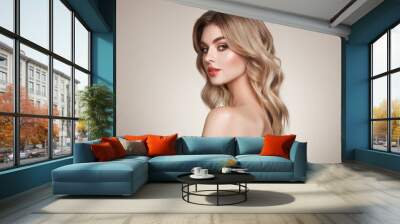 A beautiful young woman with shiny wavy blonde hair. Model with healthy skin, close up portrait. Cosmetology, beauty and spa Wall mural