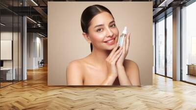 Beautiful elegant woman holding a cosmetic jar of oil serum or hyaluronic acid in her hand. Perfect facial skin Wall mural