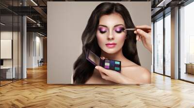 Makeup artist applies eye shadow. Beautiful woman face. Perfect makeup. Make-up detail. Beauty girl with perfect skin. Nails and manicure. Eye shadow palette Wall mural