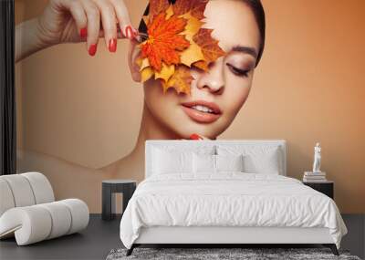 Portrait of beautiful young woman with autumn leafs. Healthy clean fresh skin natural make up beauty eyes and red nails Wall mural