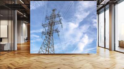 High voltage tower with electrical wires on blue sky with white clouds. Electricity transmission lines, power supply concept Wall mural