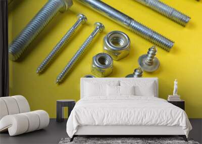 nut bolts and self-tapping screws of different sizes lie on a yellow background. close-up. Wall mural