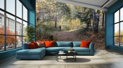 Two fishermen sit on the Bank of a forest river surrounded by colorful autumn trees Wall mural