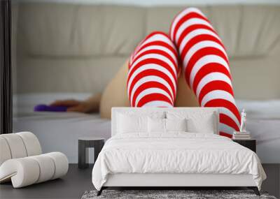 Woman in red white striped stockings laying on the bed and holding purple silicone dildo. Vibrator in female hand, sex toy Wall mural