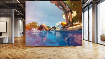 Young girl jumping in swimming pool against No jumping sign on summer holidays. Wall mural