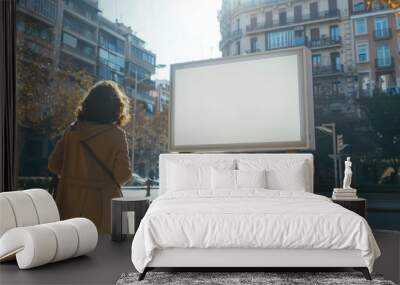 young woman stands on the street and looks at a blank billboard. mockup Wall mural