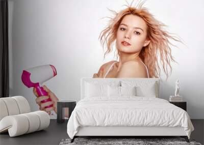 Beautiful young blonde woman with hair dryer on white background Wall mural