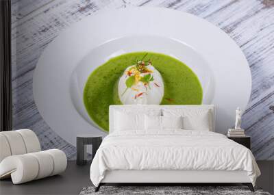 Green sauce with poached egg in white plate, closeup Wall mural