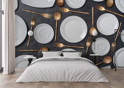 Many white empty ceramic plate and brass forks and spoons on black background Wall mural