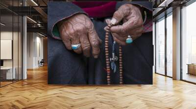 Old Tibetan woman holding buddhist rosary in Hemis monastery, Ladakh, India. Hand and rosary, close up Wall mural